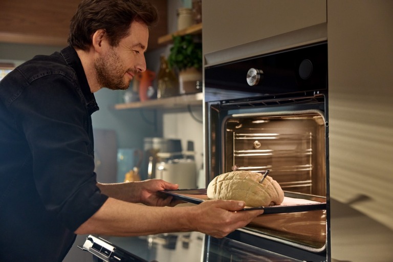 homme met au four son pain réalisé au robot de cuisine avec sonde pour mesurer la température